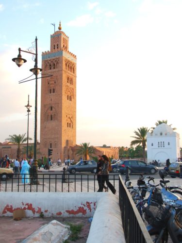 De minaret van de Koutoubia-moskee en het witte koepelgraf van een vrouwelijke heilige in Marrakech, Marokko.