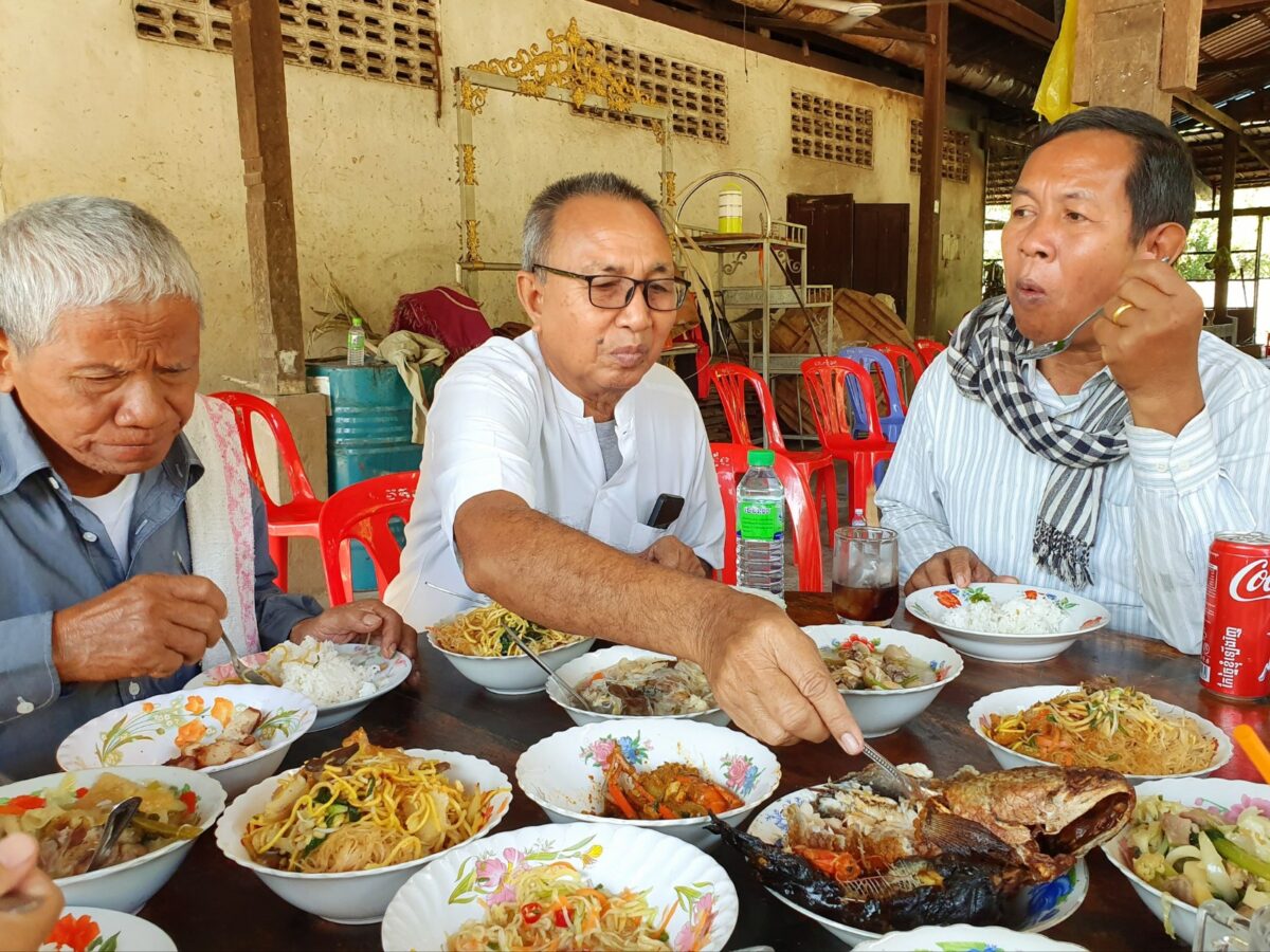 Leken eten de restjes van de lunch van monniken in de pagode van Odambang, Cambodja