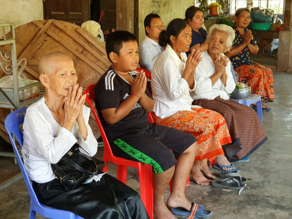 Nonnen en leken chanten met de handen gevouwen in de pagode van Odambang, Cambodja