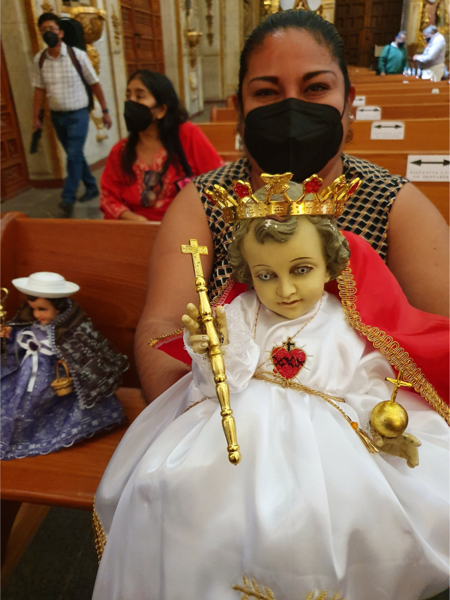 Mexicaanse gelovige toont trots haar Niño Dios of Jezuspop met witte jurk en kroontje