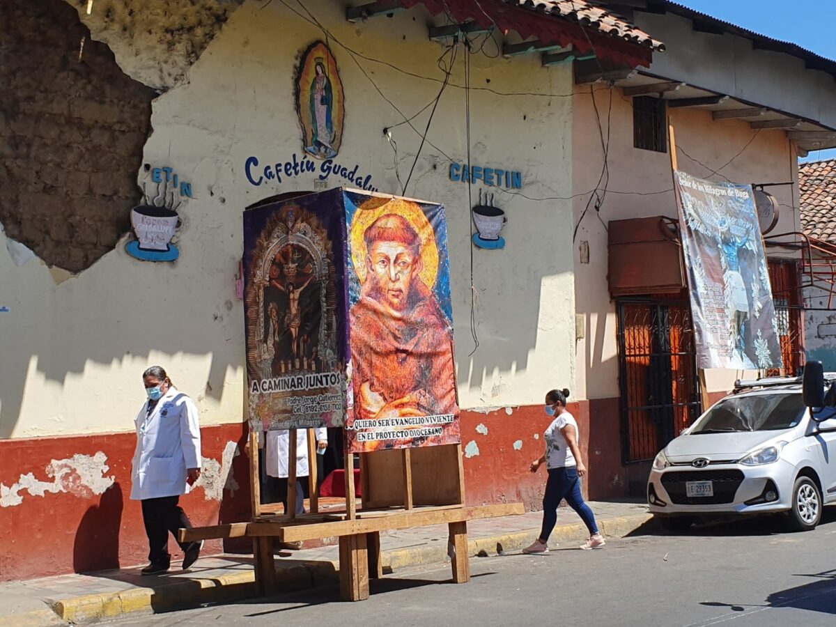 Afbeeldingen van heiligen op posters en een muur in een straat in León, Nicaragua