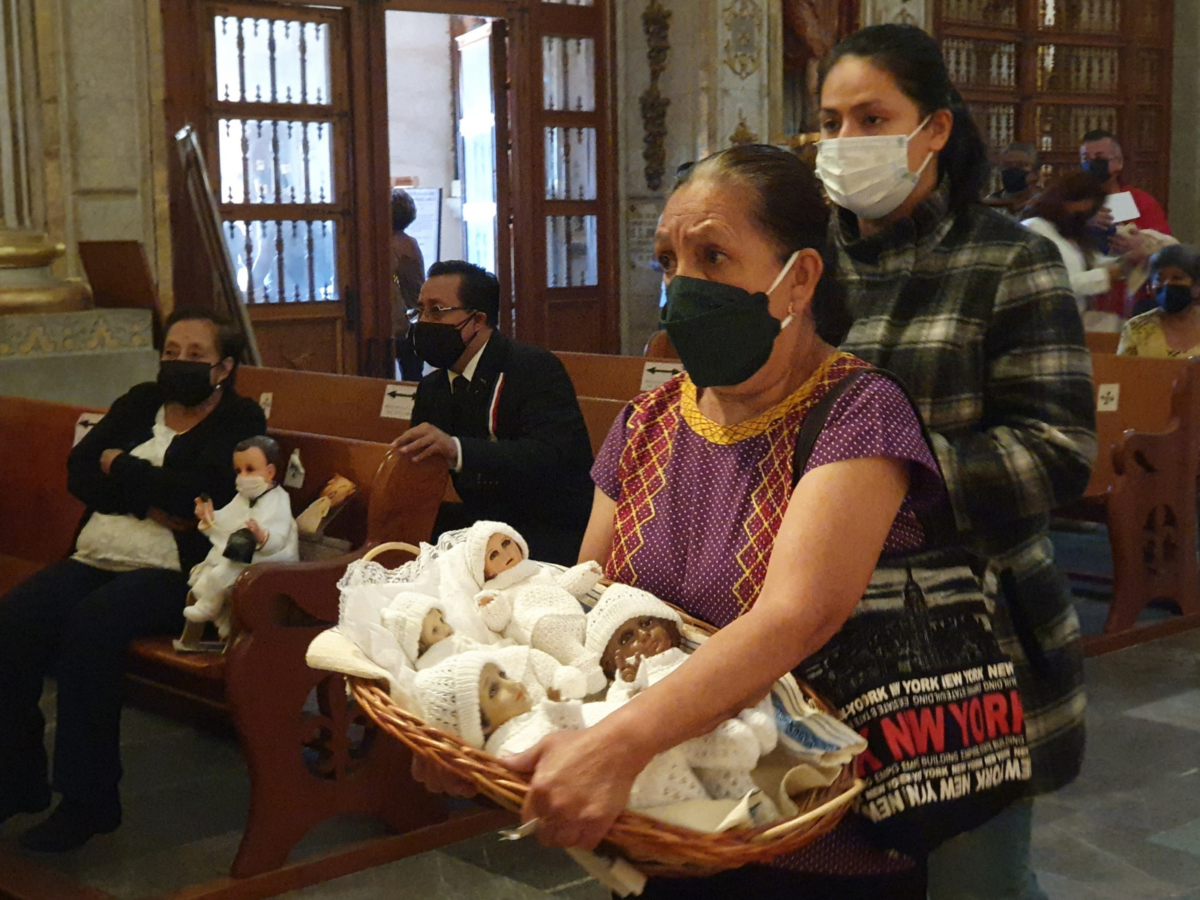 Mexicaanse gelovige met vier Niños Dios in de wachtrij voor inzegening in een kerk in Oaxaca