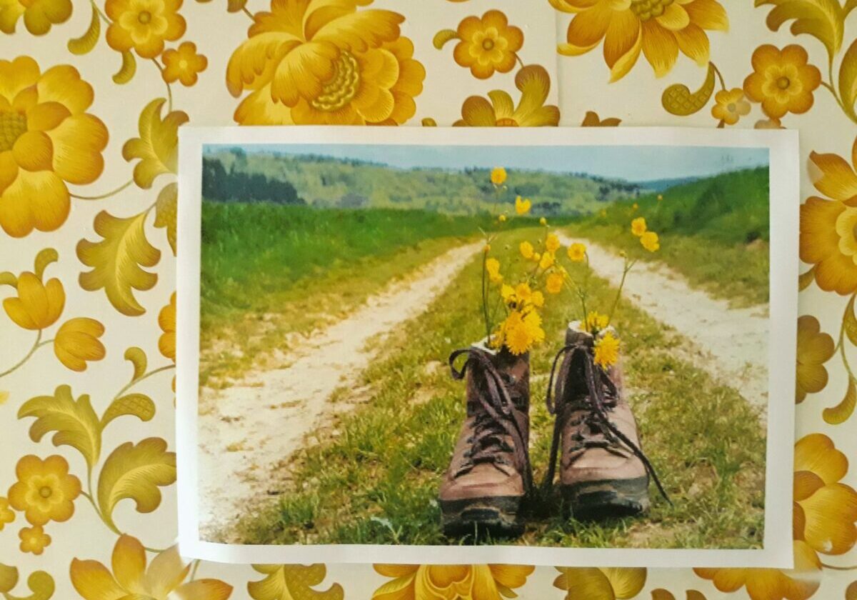 Schilderij van wandelschoenen gevuld met boterbloemen en paardenbloemen